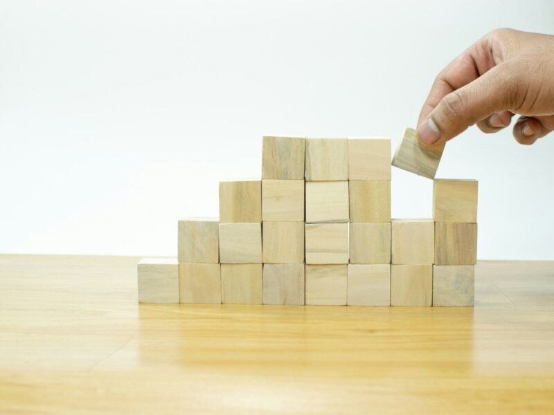 A person placing a block into a pile of wooden blocks